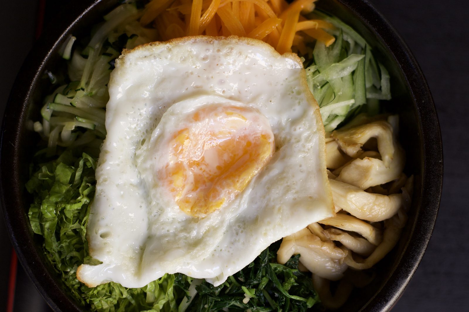 Bibimbap — rice, vegetables and a fried egg in a stone bowl